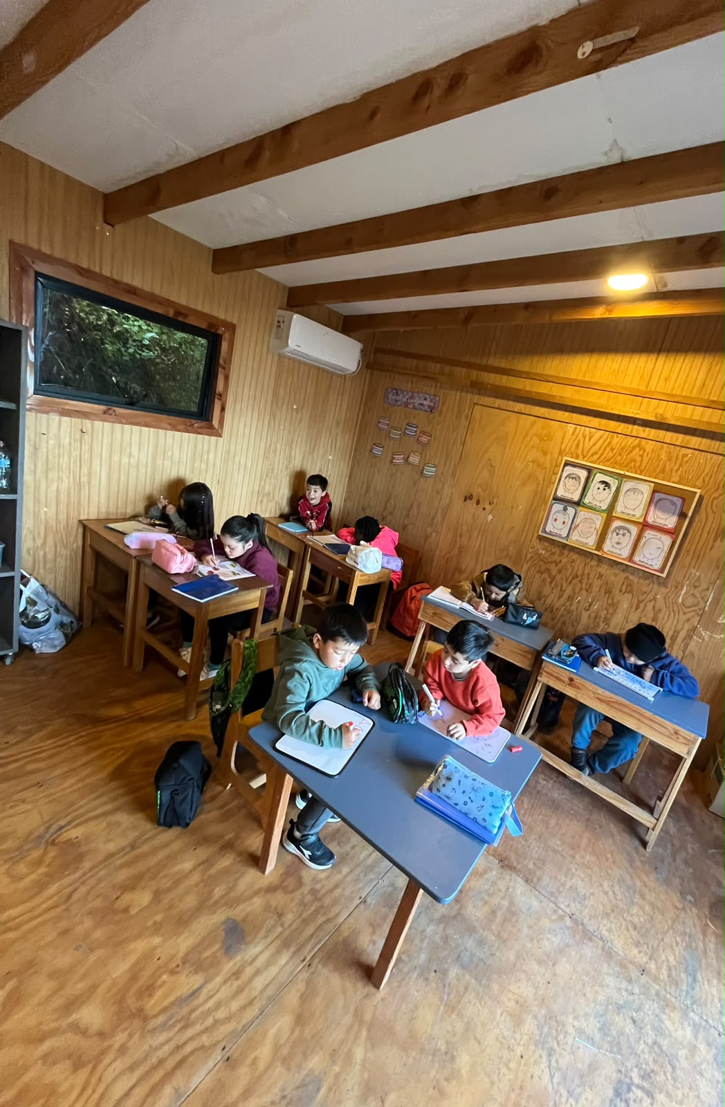 Estudiantes trabajando en sus mesas dentro de una sala de clases