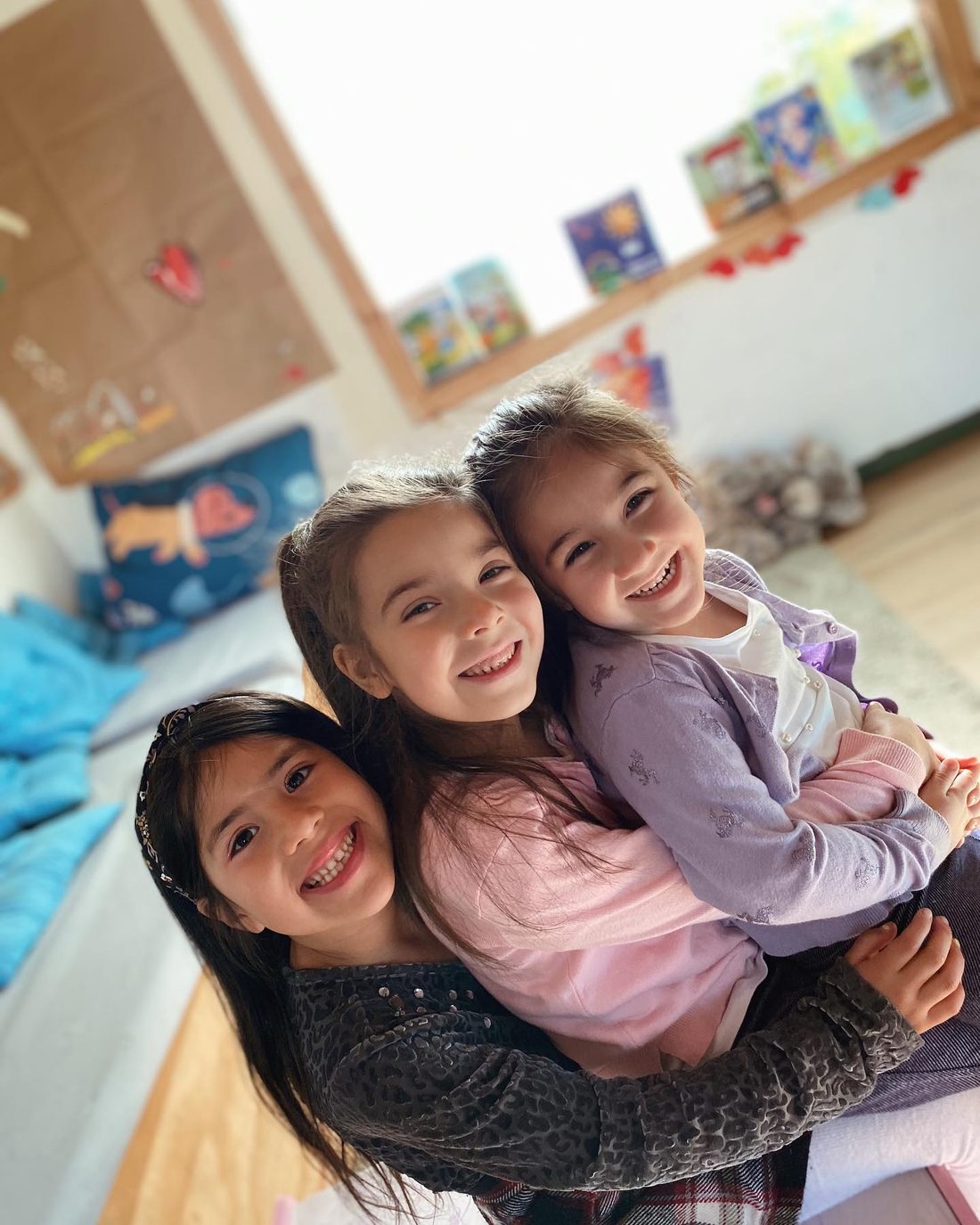 Educadora abrazando a dos niños pequeños en el colegio